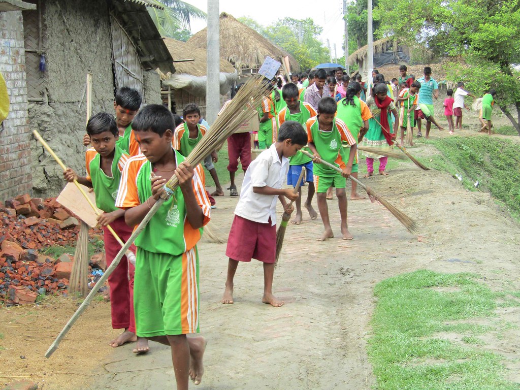 school children cleaning their residential area in village
