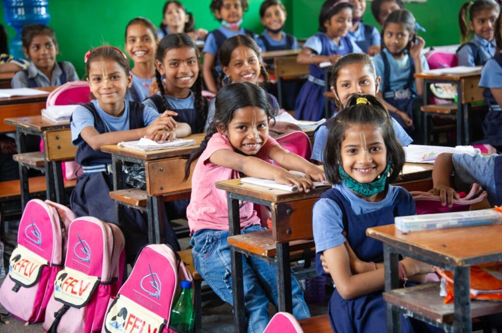 girls happily sitting on benches in class