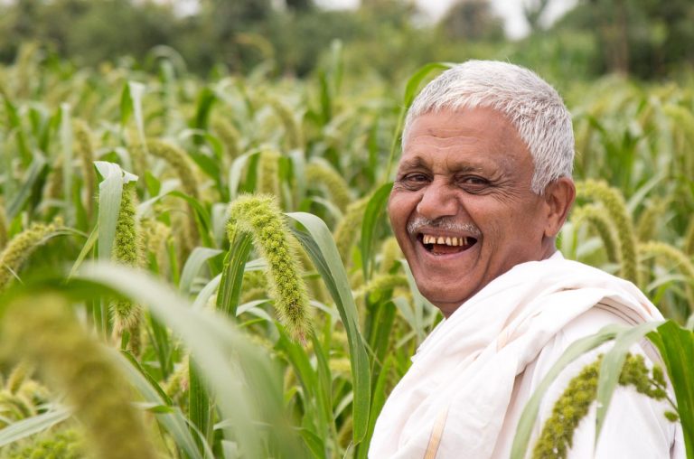 A farmer is very happy to see his crop and he's standing in his field