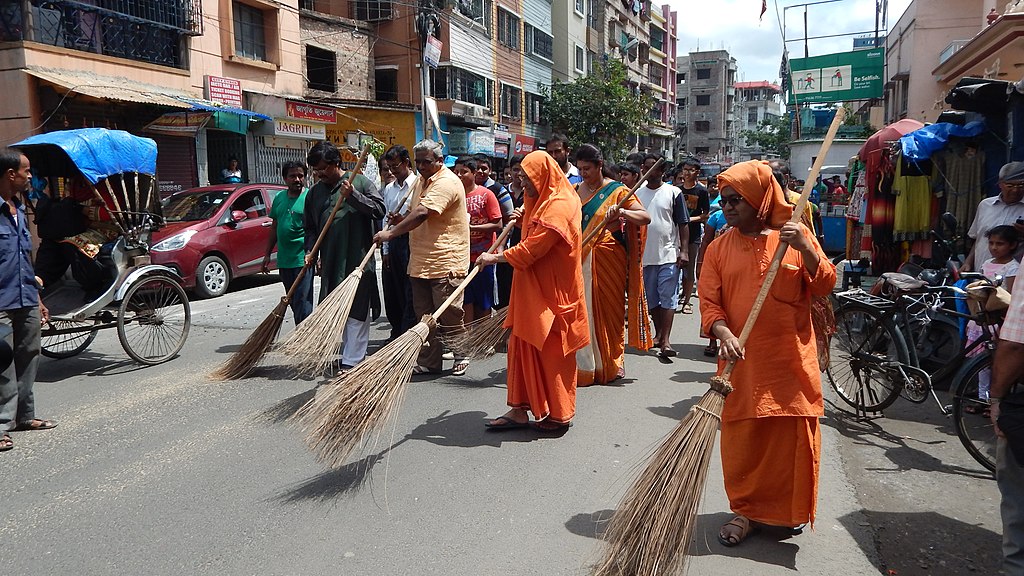 some people are cleaning the road with brooms
