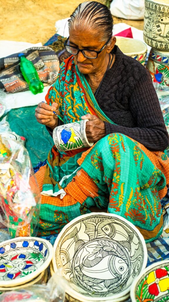 a woman sitting on the ground working on a piece of art